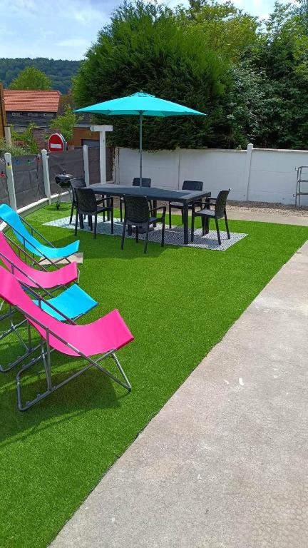 une table de pique-nique et des chaises avec un parasol sur l'herbe dans l'établissement Le clos des rêves à 5km de dieppe, à Martin-Église