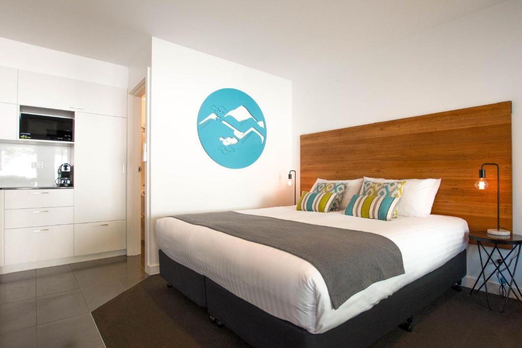 sypialnia z dużym łóżkiem z niebieskim znakiem na ścianie w obiekcie Bright Colonial Motel w mieście Bright
