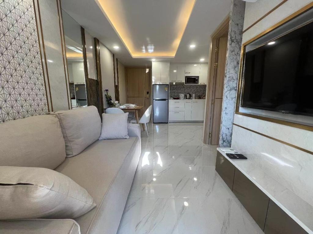 a living room with a couch and a flat screen tv at Romantic beach apartment芭堤雅水系高档酒店式公寓可做饭 in Jomtien Beach