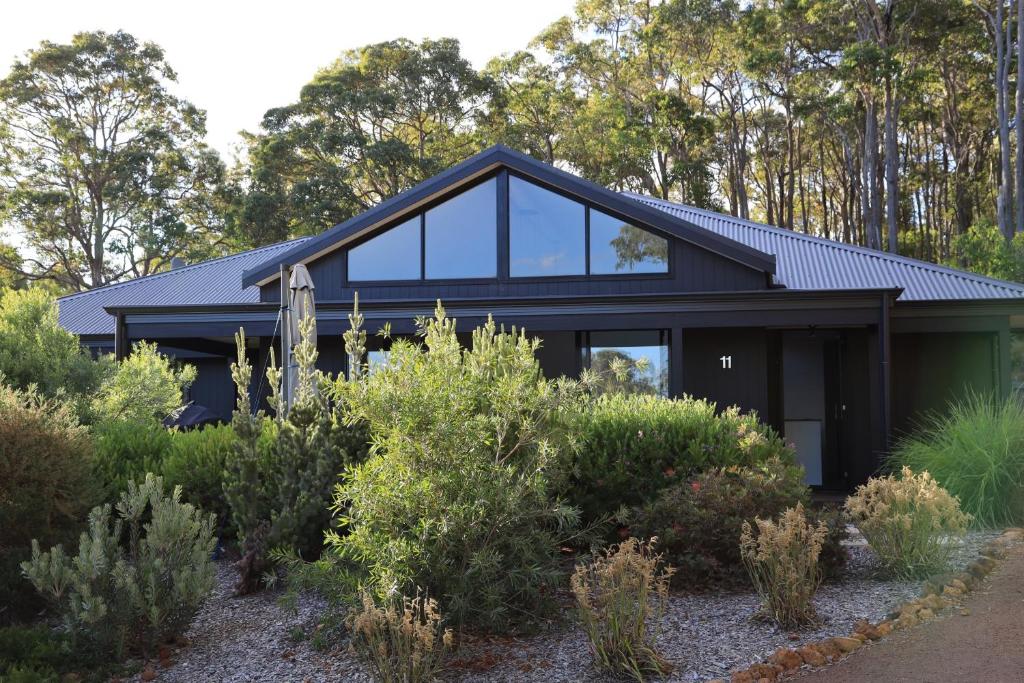 a black house with glass windows and bushes at Villa Vines @ Rivendell Winery Estate in Yallingup Siding