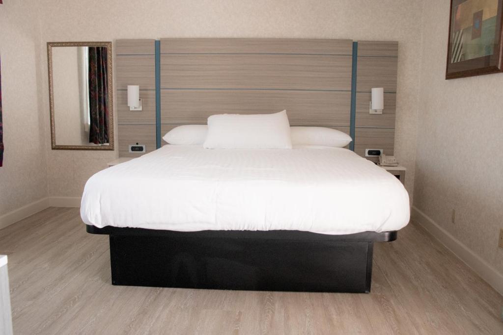 a bedroom with a large bed with white sheets at Discovery Inn in Hayward
