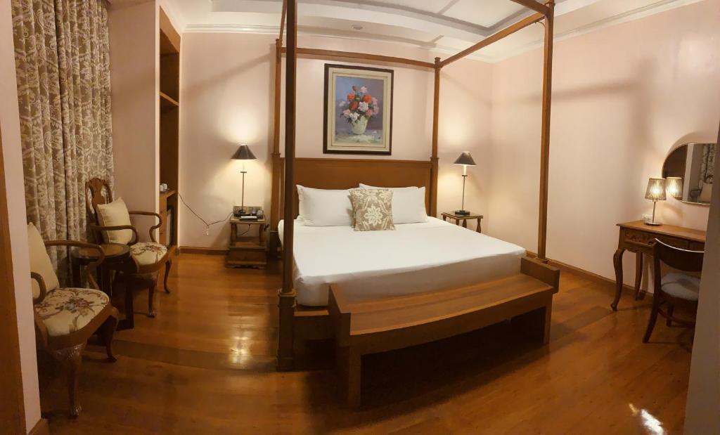 1 dormitorio con 1 cama, mesa y sillas en Sarita Bed and Breakfast, en Laoag