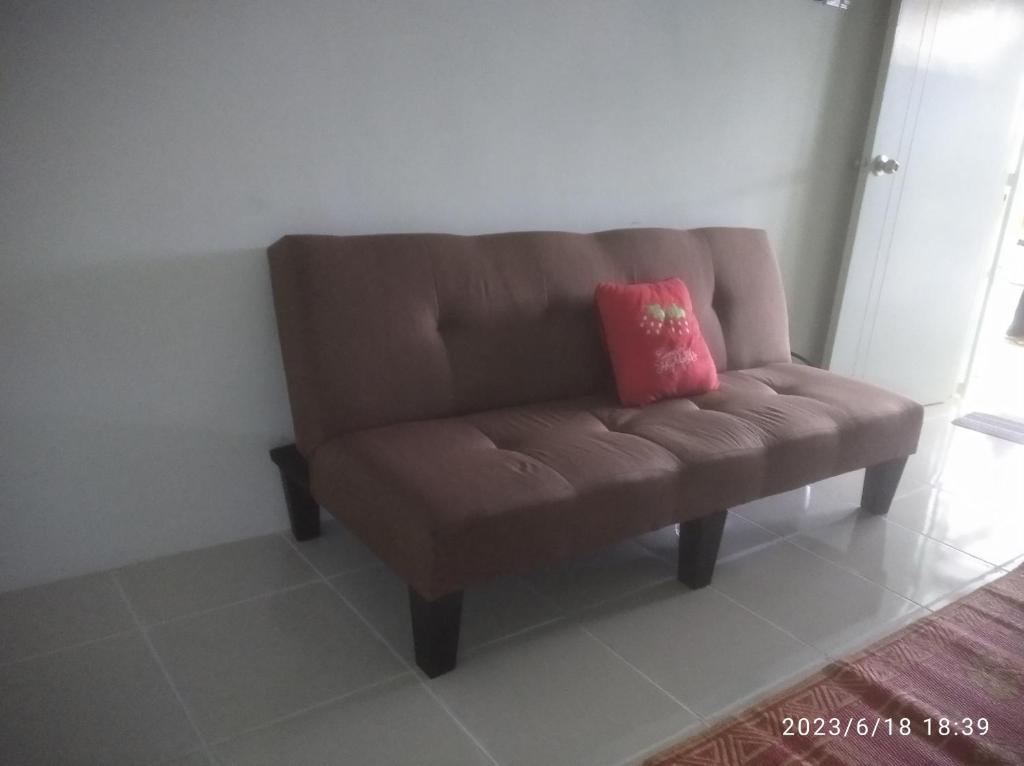 LunasにあるRumah Lunasのピンクの枕が付いた茶色のソファ(客室内)
