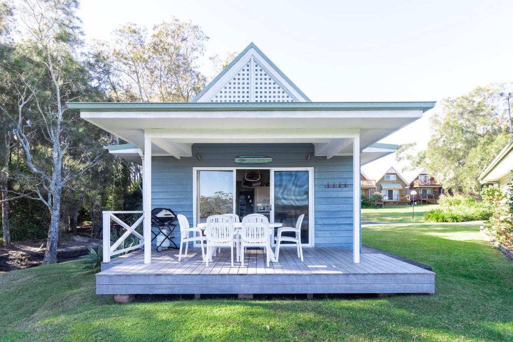 une maison bleue avec une terrasse munie de chaises dans l'établissement Beach Shack on the Lagoon, à Berrara