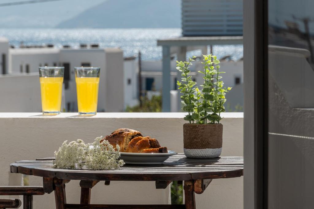 una mesa con un plato de pan y dos vasos de zumo de naranja en Golden Silence Studios, en Agios Prokopios