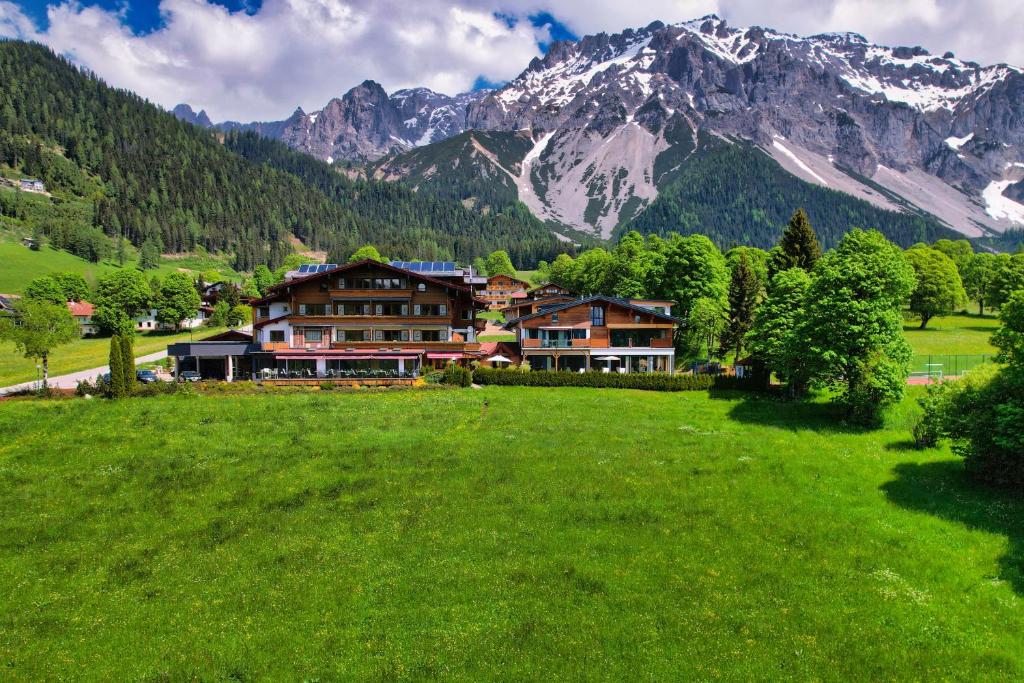 una casa en un campo con una montaña en el fondo en Landhaus Ramsau en Ramsau am Dachstein