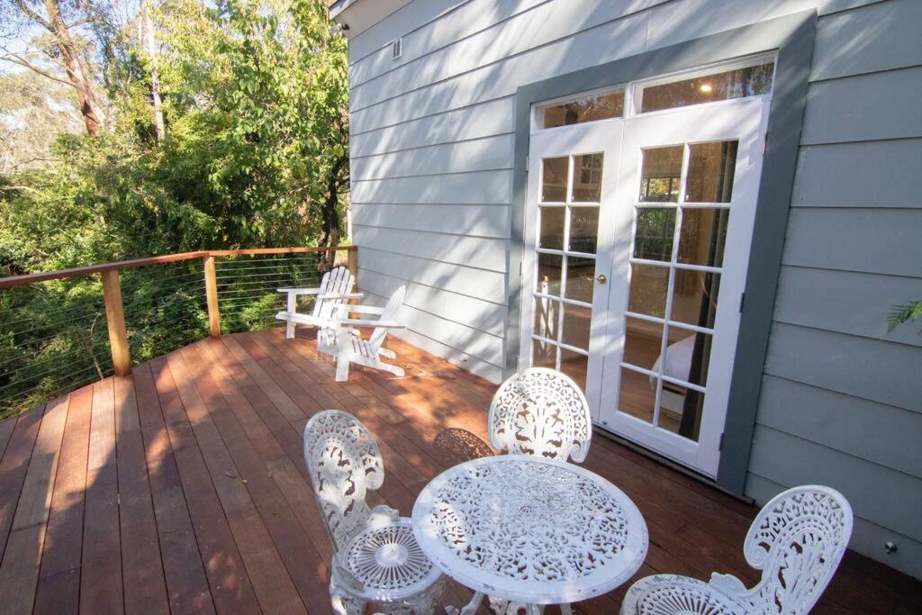 un patio con mesa y sillas en una terraza en Bottlebrush Cabin, cosy private cabin in the trees, en Leura
