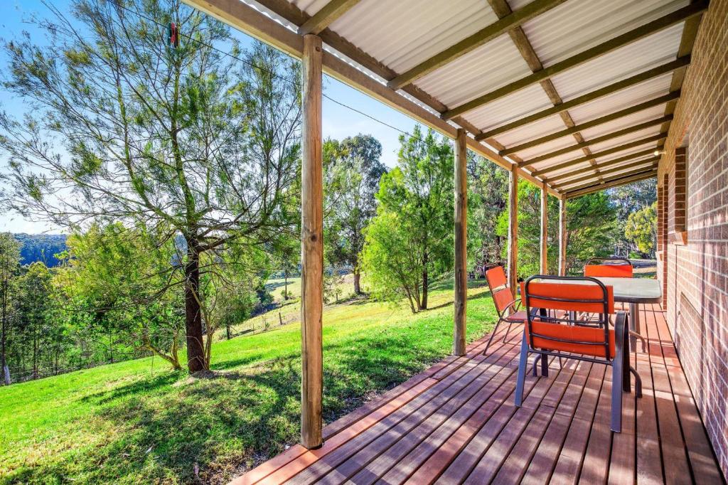 a wooden porch with a table and chairs on it at Braeside Cabin Two Alphitonia in Central Tilba