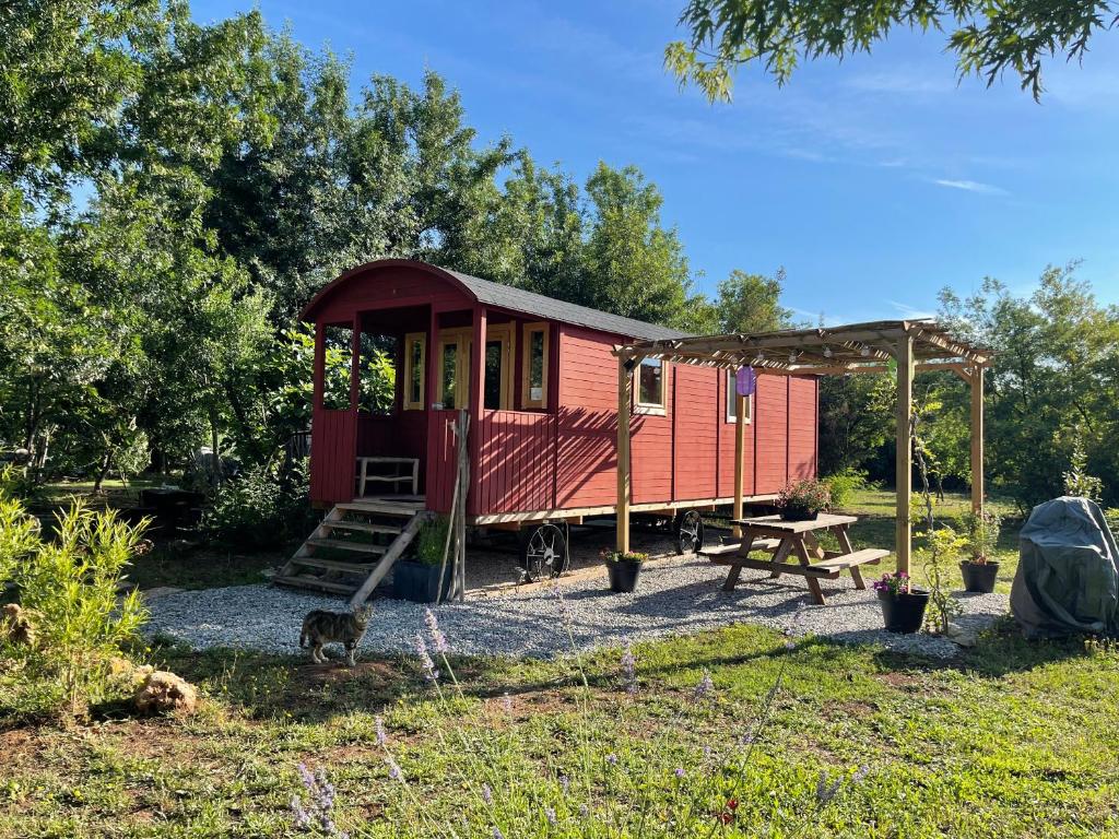 une petite maison rouge avec une table de pique-nique et une tente dans l'établissement Roulotte , hébergement atypique, à Solliès-Pont