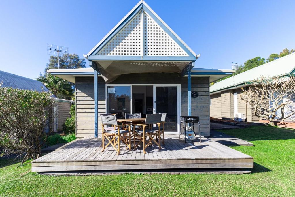 a house with a deck with a table and chairs at Kangaroo Cabin in Berrara