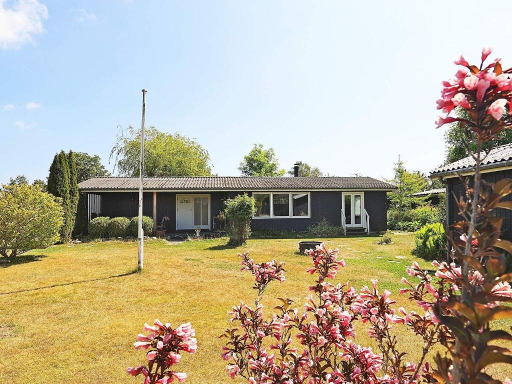 una casa con un patio con flores rosas en Holiday home Faxe Ladeplads IX, en Fakse Ladeplads