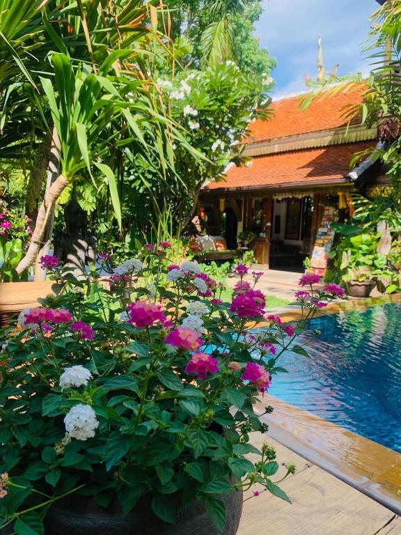 A flower-filled poolside garden beside a traditional wooden building.