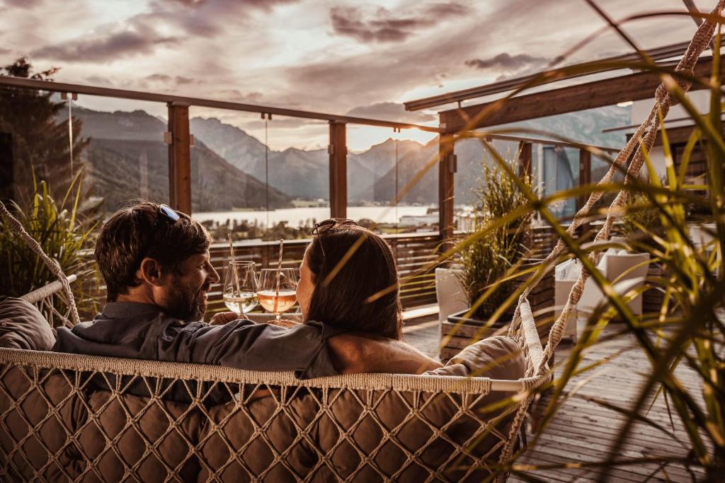 a man and a woman sitting in a hammock at Hotel St. Georg zum See in Maurach