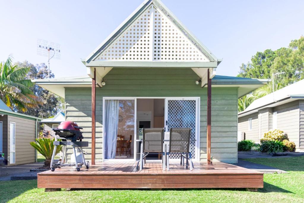 ein kleines grünes Haus mit einer Holzterrasse in der Unterkunft Nannys Beach House in Berrara