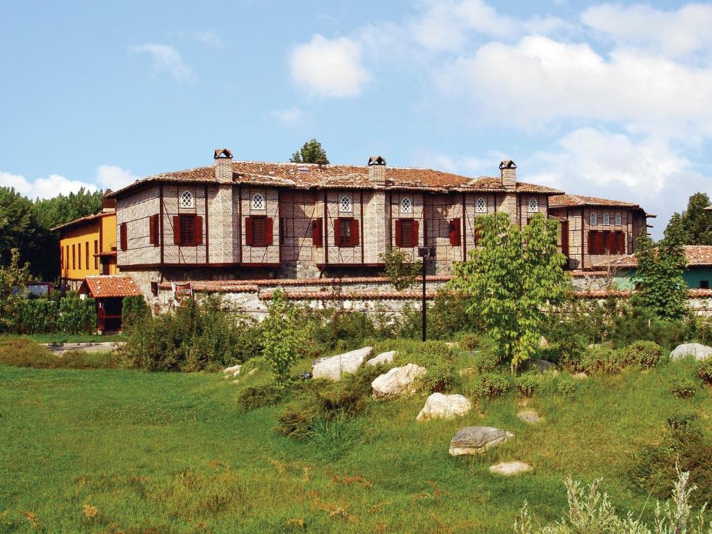 una casa vieja en un campo frente a un edificio en Otantik Hotel & Spa, en Bursa