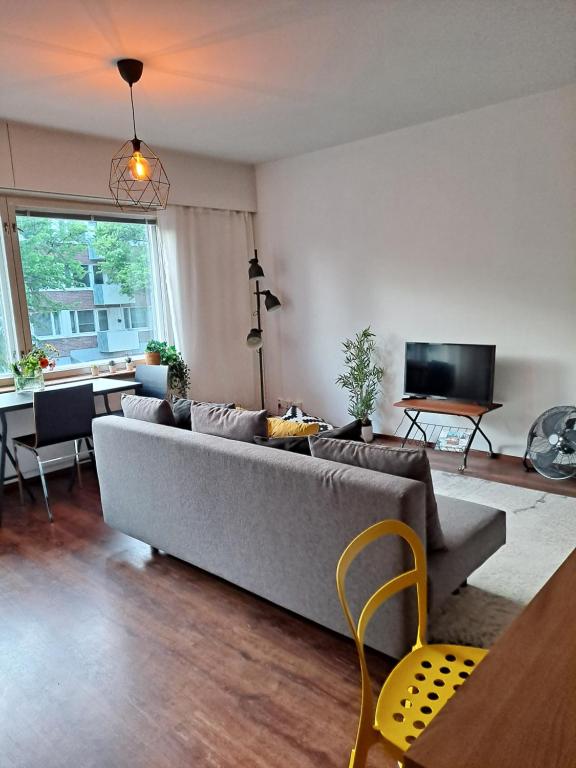 uma sala de estar com um sofá cinzento e uma mesa em Puotilan idylli meren lähellä em Helsinque