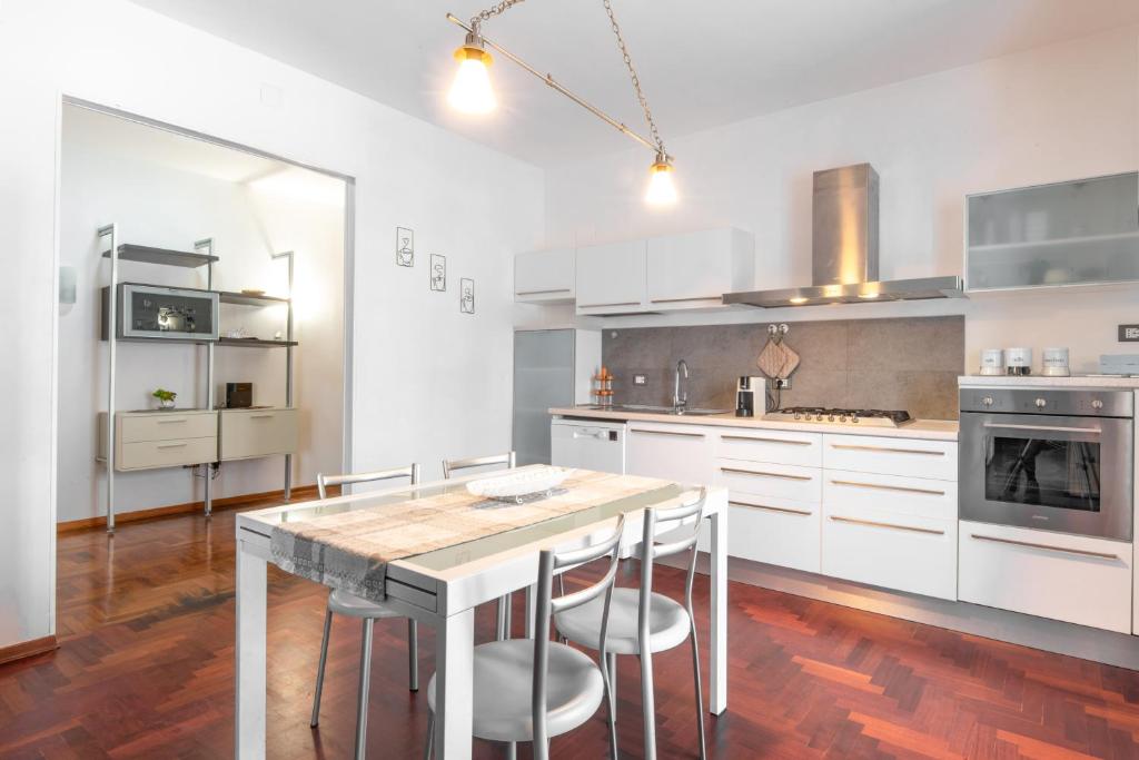 eine Küche mit weißen Schränken und einem Tisch mit Stühlen in der Unterkunft Piombino Apartments - Casa Marconi in Piombino