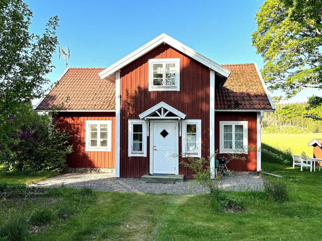 czerwony dom z białymi drzwiami na dziedzińcu w obiekcie Holiday home Tystberga III w mieście Tystberga