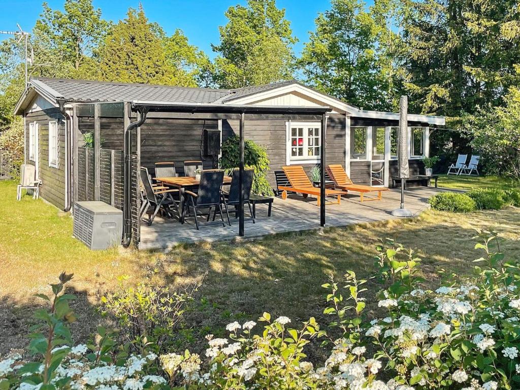 eine Hütte mit einer Terrasse mit einem Tisch und Stühlen in der Unterkunft Holiday home SÖLVESBORG X in Sölvesborg
