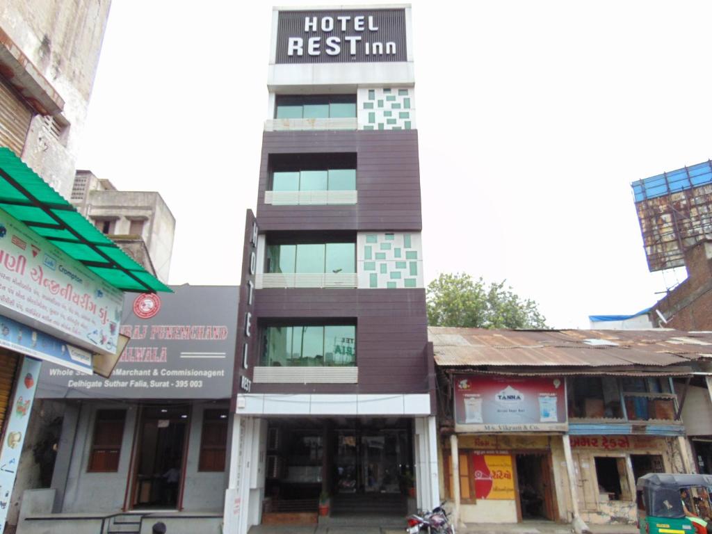 a building on the corner of a street at HOTEL REST INN in Surat