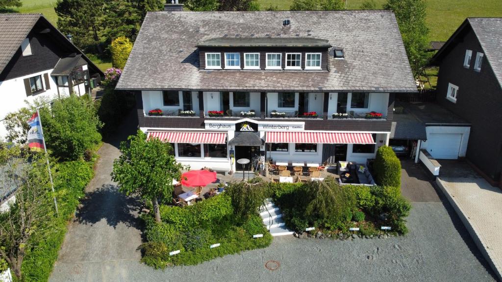 Elle offre une vue aérienne sur une maison dotée d'une terrasse. dans l'établissement Berghaus Winterberg, à Winterberg