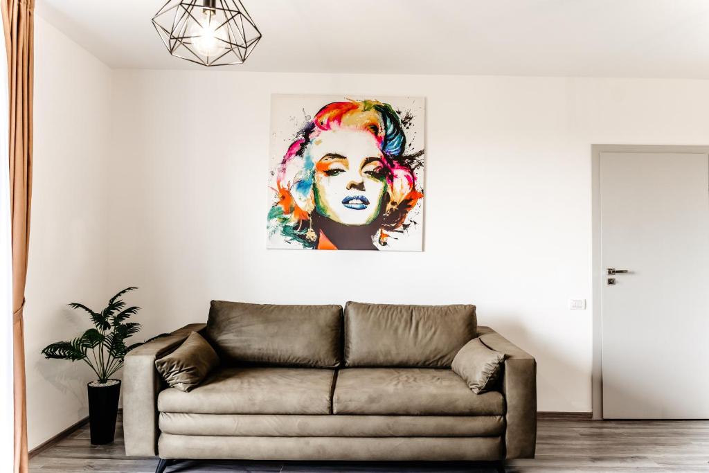 una sala de estar con sofá y una pintura de una mujer en Ego Apartments, en Băile Felix