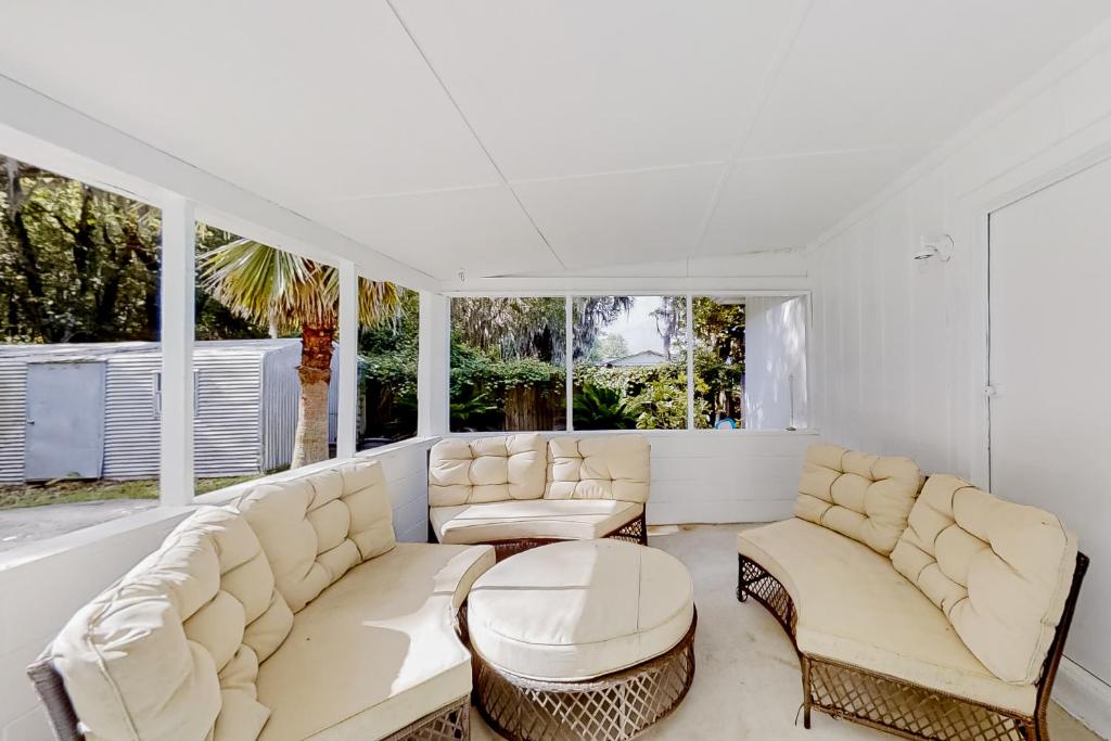a living room with white furniture and windows at The Saltwater Cottage in Jacksonville