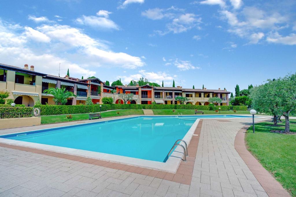 a large swimming pool in a yard with buildings in the background at -Free Parking & Pool- Casa a pochi passi dal Lago in Padenghe sul Garda