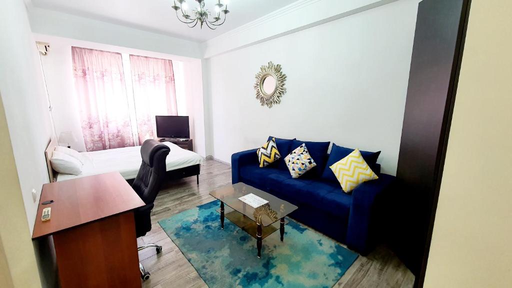 een woonkamer met een blauwe bank en een tafel bij FlatRent Apartment in Bisjkek