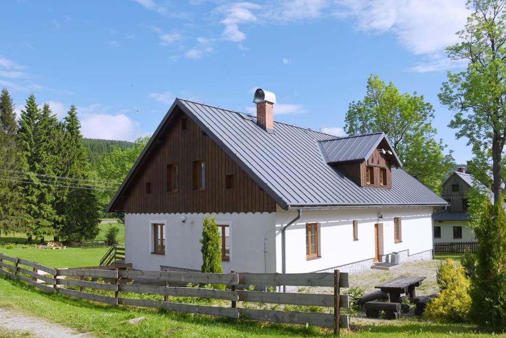 a white barn with a black roof at Chata Zahálka Ramzová in Ostružná