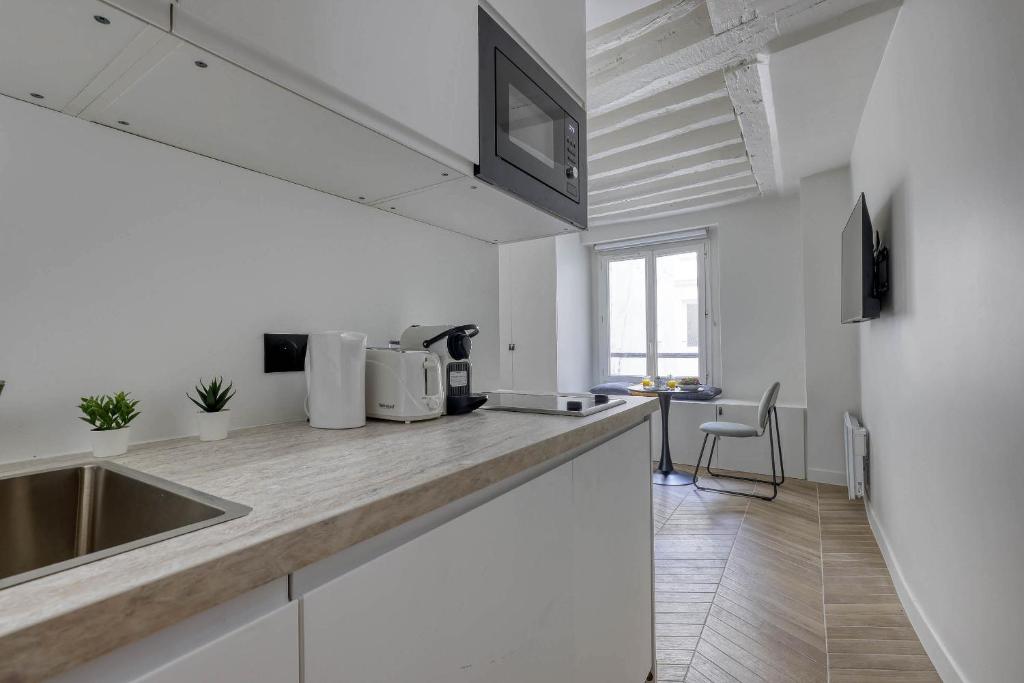 a white kitchen with a sink and a counter top at New and Designed Studio well Equipped - Heart of Paris 2 in Paris