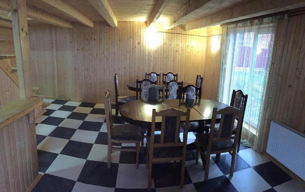 ein Esszimmer mit einem Tisch und Stühlen auf einem karierten Boden in der Unterkunft Котеджі Зоряне Небо in Bukowel