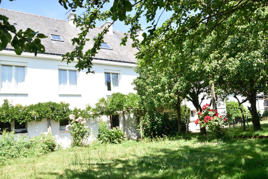 ein weißes Haus mit Bäumen und Blumen im Hof in der Unterkunft Le clos argoat in Pontivy