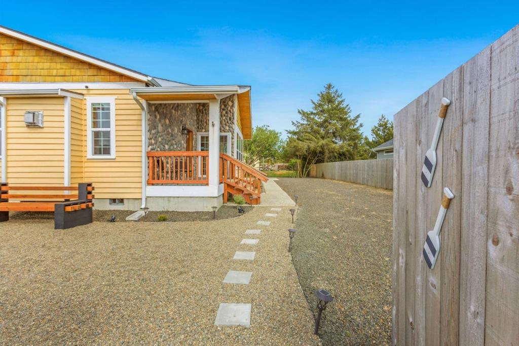 uma casa amarela com uma cerca e um alpendre em Cobblestone Cottage em Ocean Shores