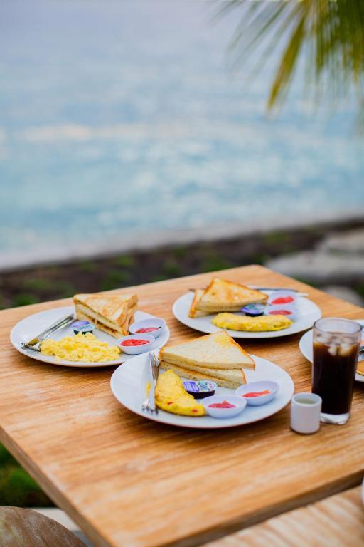 un tavolo in legno con piatti di panini e bevande di Penida Paradiso a Klungkung