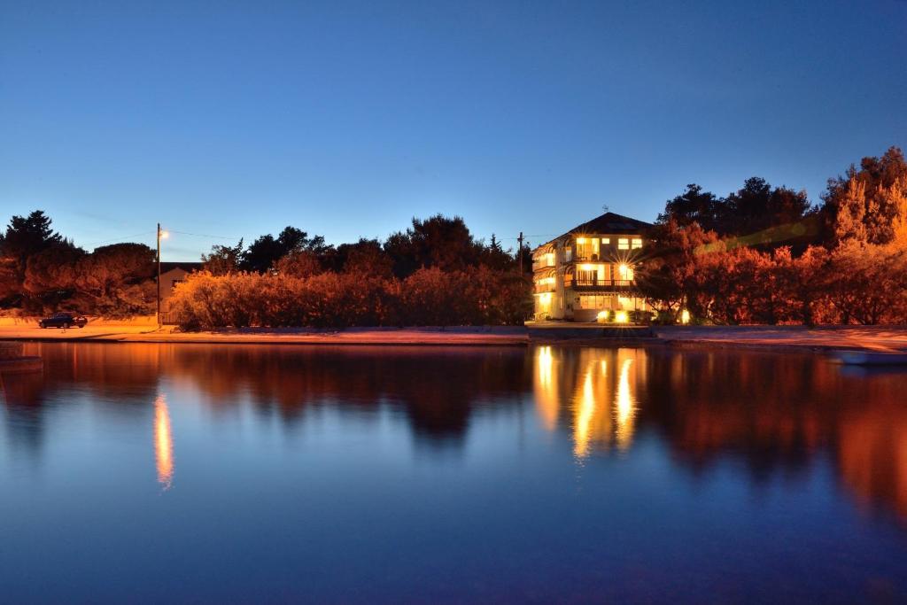 a house on the shore of a lake at night at Guest House Malenica in Sukošan