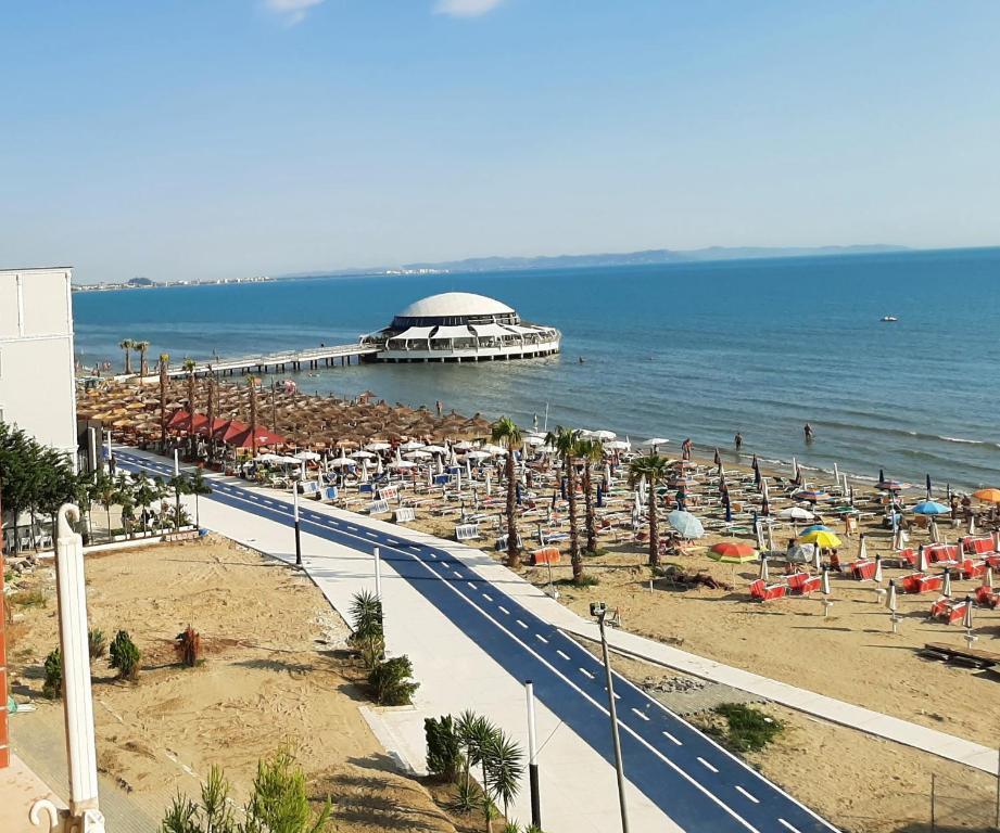 een strand met een weg en parasols en de oceaan bij Mani Apartment in Durrës