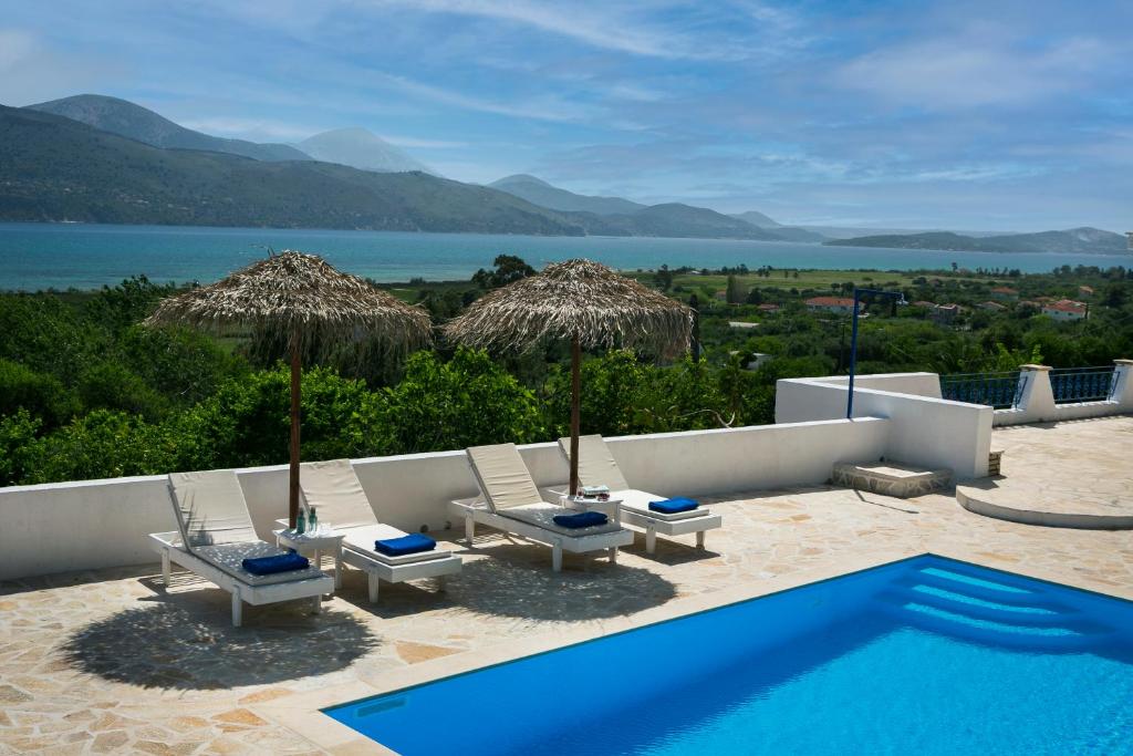 a swimming pool with chairs and umbrellas next to a swimming pool at Villa Afrodite in Lixouri