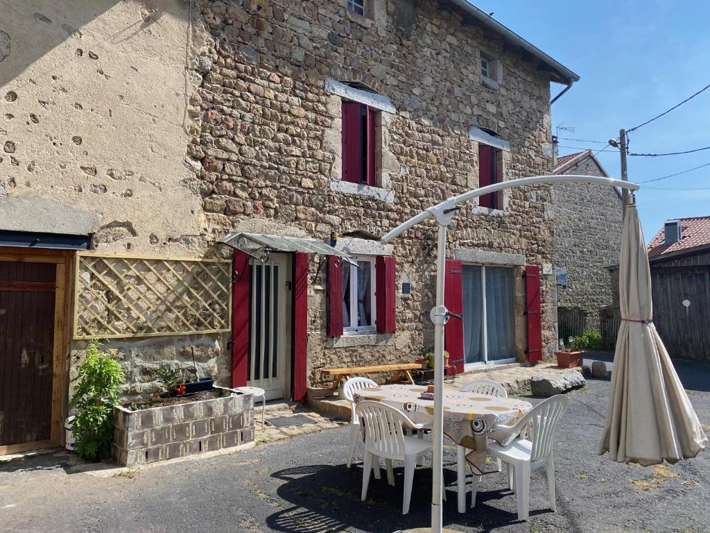 a table and chairs and an umbrella in front of a building at CHAMBRE D HOTES CHEZ DANY MAOWMAOW ET GARFIELD in Bellevue-la-Montagne