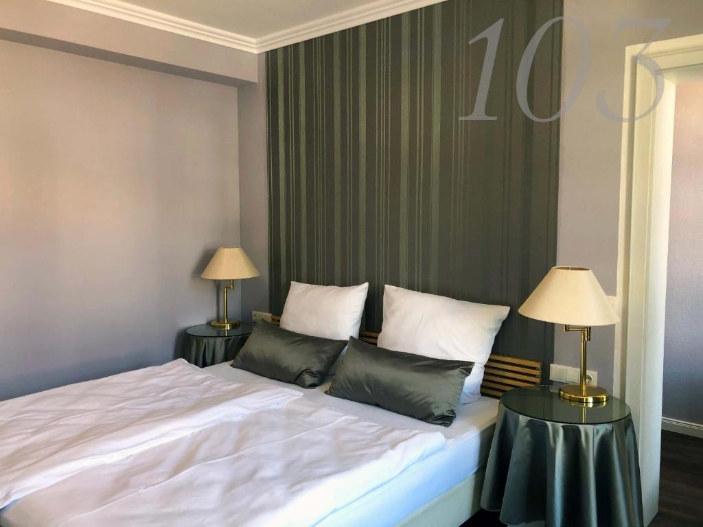 Rein Klassik Hotel في باد بيرمونت: غرفة نوم مع سرير وطاولتين مع مصابيح