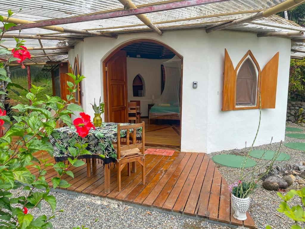 uma pequena casa com uma mesa e cadeiras num deque de madeira em Paradiselodge Casa Romantica em Platanillo
