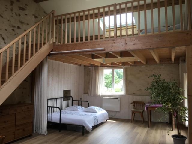 a bedroom with a bed under a wooden staircase at Loft Sud-Nantes in Le Bignon