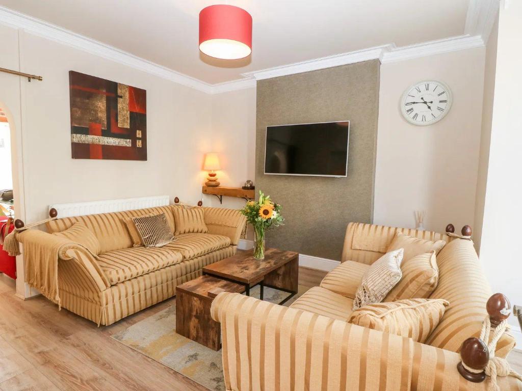 a living room with two couches and a clock on the wall at Llandudno 3 Bedroom Holiday Apartment in Town Centre in Llandudno
