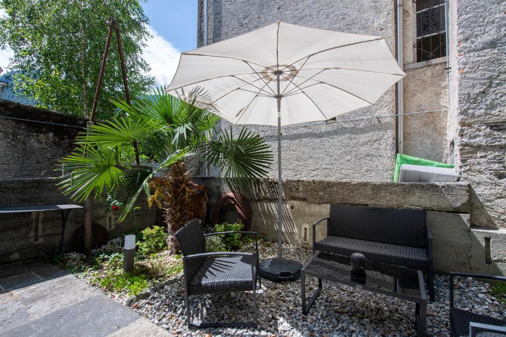 a patio with a bench and an umbrella at Residenza La Serenata - Happy Rentals in Cavigliano