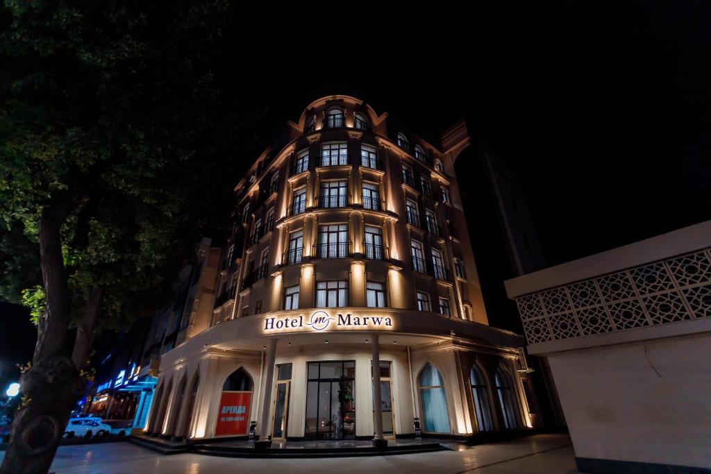 un edificio iluminado con un cartel en él por la noche en Hotel Marwa Tashkent Pool&Spa en Tashkent