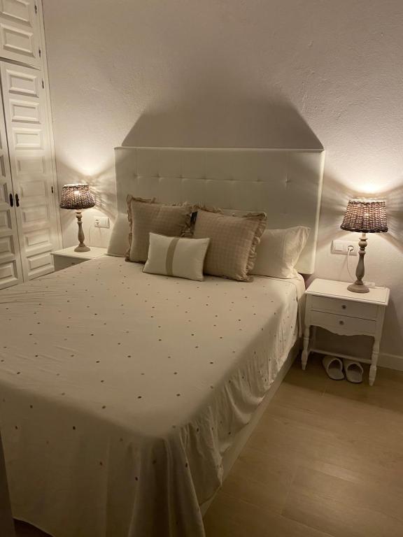 a bedroom with a large white bed with two lamps at Precioso estudio a 300m de la playa in Platja d'Aro