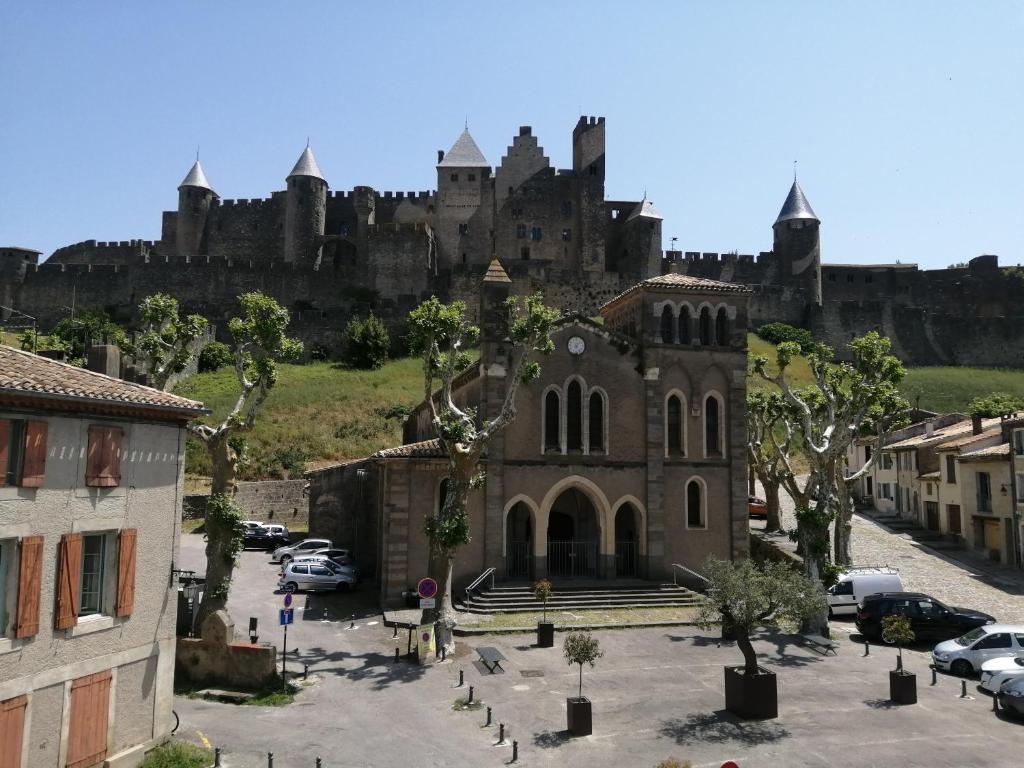 un antiguo edificio con un castillo en el fondo en Le Bokeh - Face à la Cité Médiévale, en Carcassonne