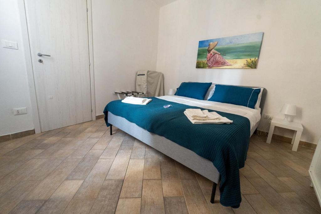 een slaapkamer met een bed met blauwe lakens en een houten vloer bij Le Casette di Didi in Trapani