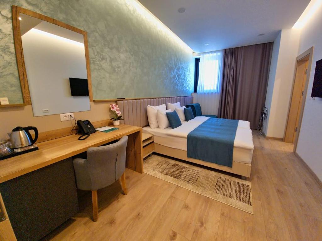 Habitación de hotel con cama, escritorio y espejo. en Hotel Emerald, en Mostar