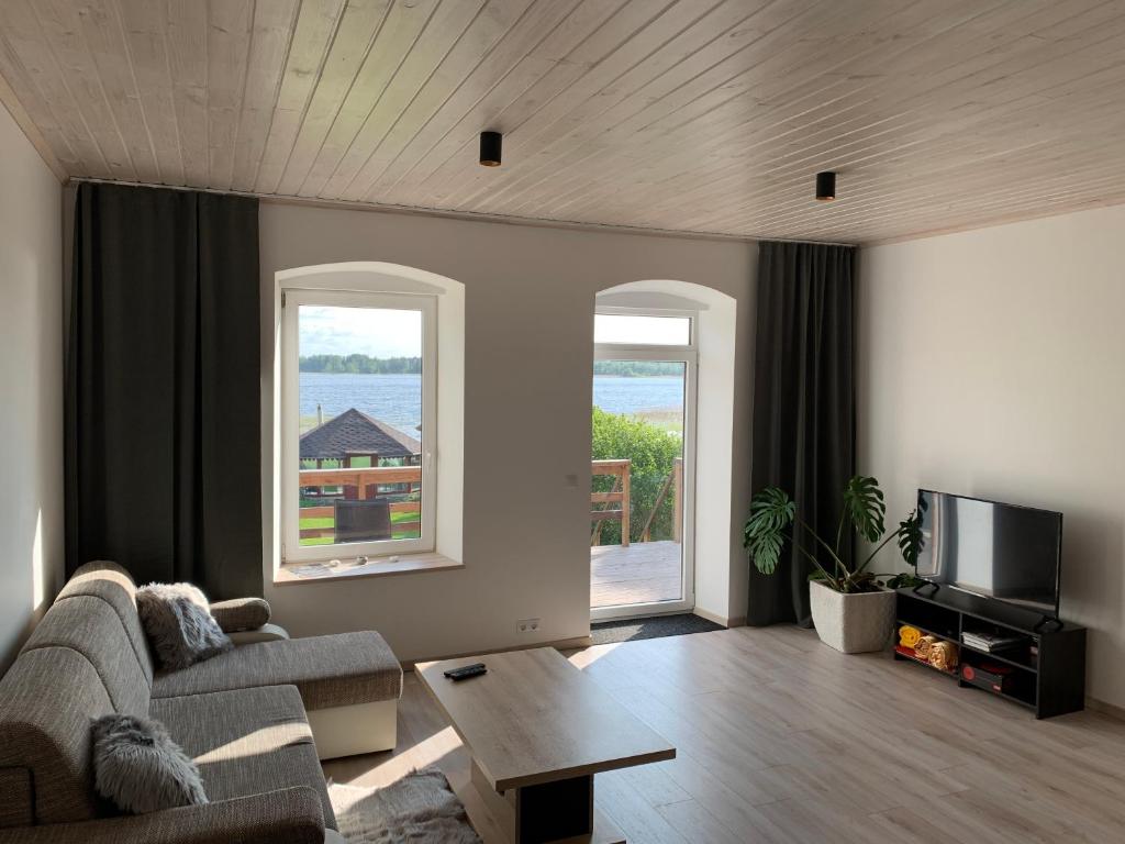 a living room with a couch and a tv at TaaliHomes Kuremaa ridaelamu järve kaldal - saun hinnas in Kuremaa